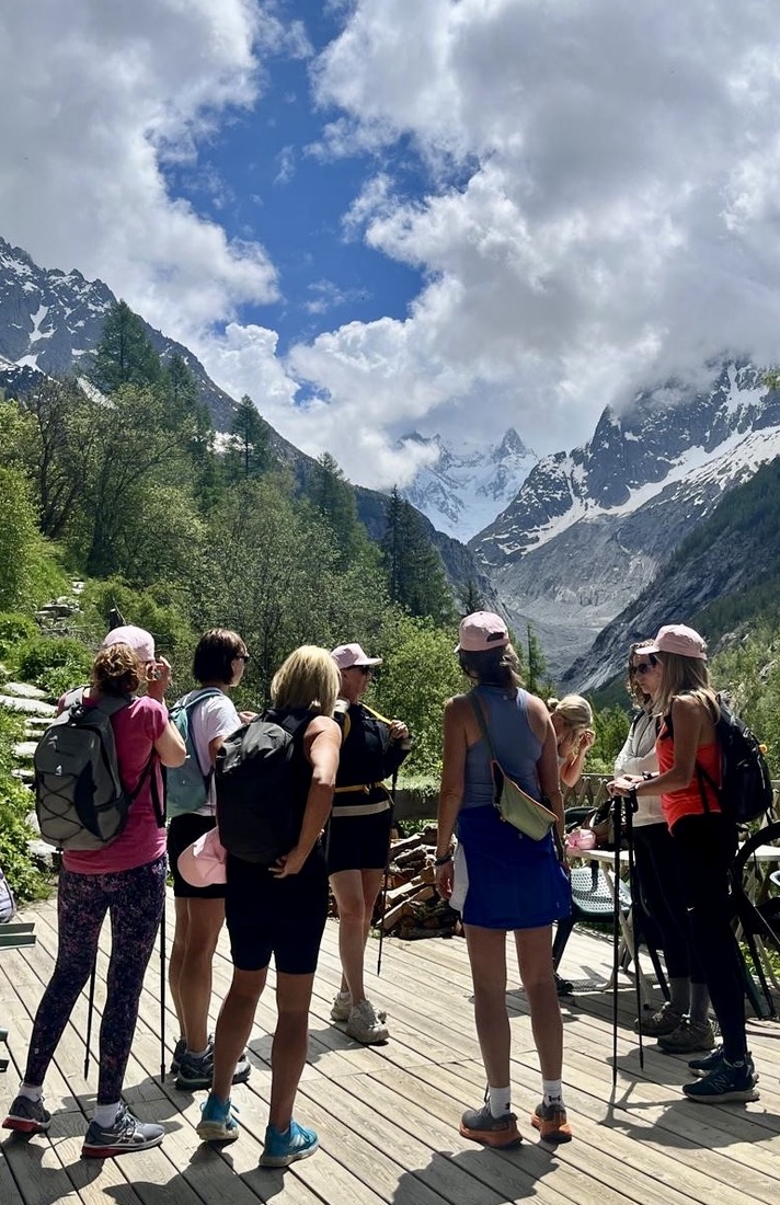 Group of women in pink caps with hiking poles taking in the snowy peaks above Chamonix